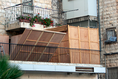 Photo of a balcony with a sukkah hut built on it.